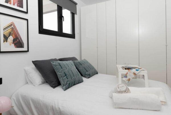 Dormitorio reformado con armarios empotrados y decoración minimalista tras reforma integral.