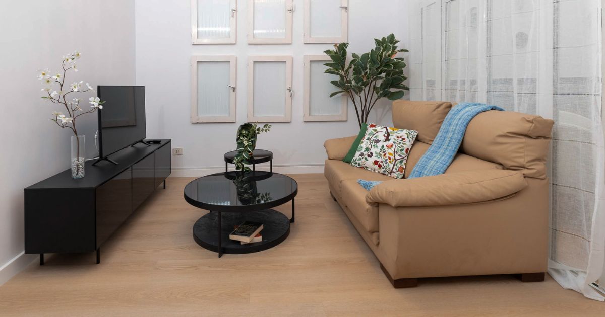 Salón reformado con sofá beige, mobiliario negro y decoración moderna en Gran Canaria